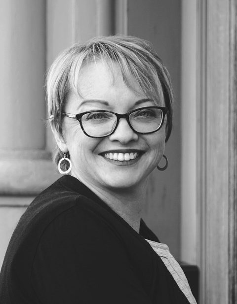 Julie C. Evans, smiling, outdoors against a stone column.