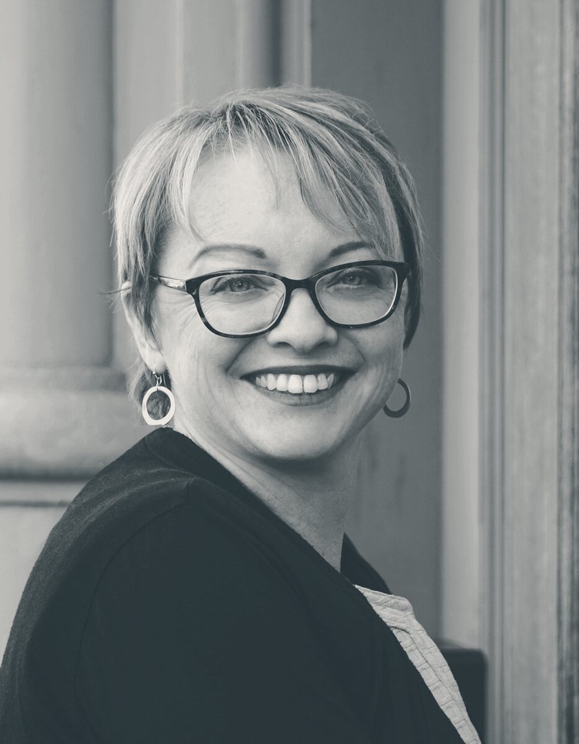 Julie C. Evans, smiling, outdoors against a stone column.